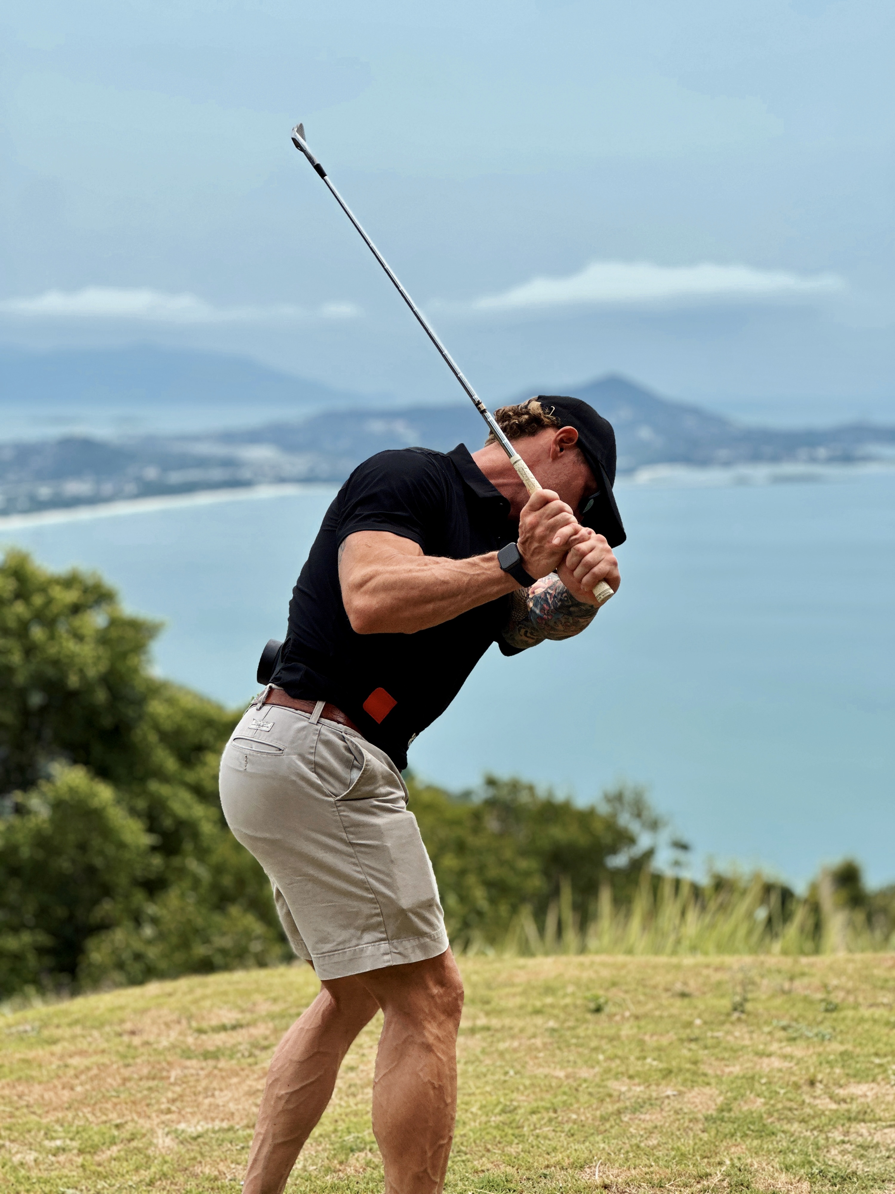 Golfer at top of backswing on coastal course — rotational power and recovery
